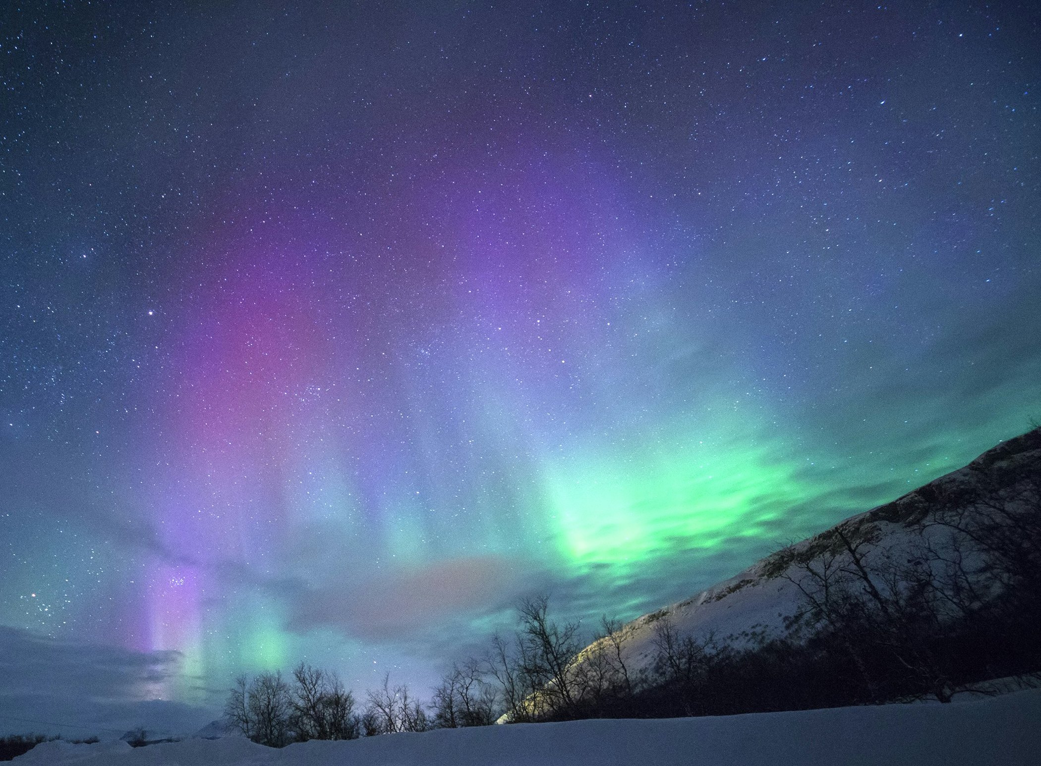 Aurora boreal encendida sobre las montañas nevadas del norte